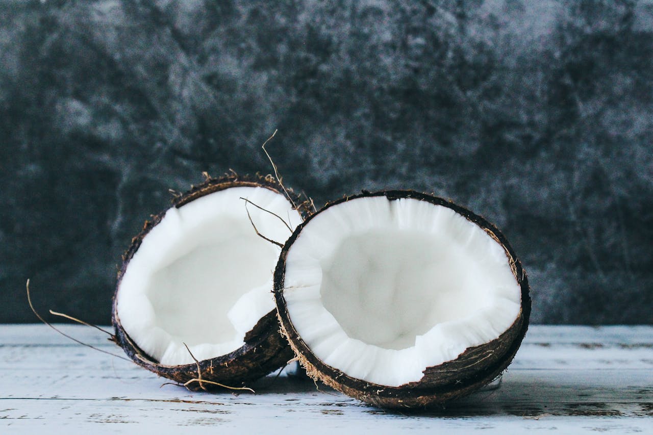Halved coconut on rustic background, showcasing fresh and nutritious white flesh.